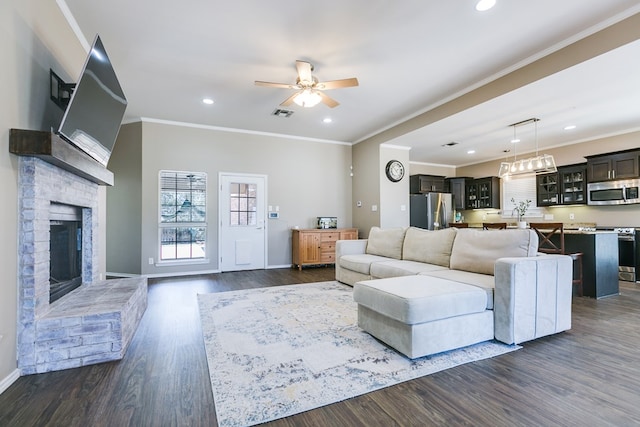 living room with ceiling fan, ornamental molding, dark hardwood / wood-style floors, and a brick fireplace