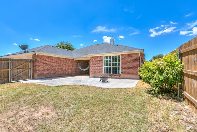 rear view of property with an outdoor fire pit, a yard, and a patio area