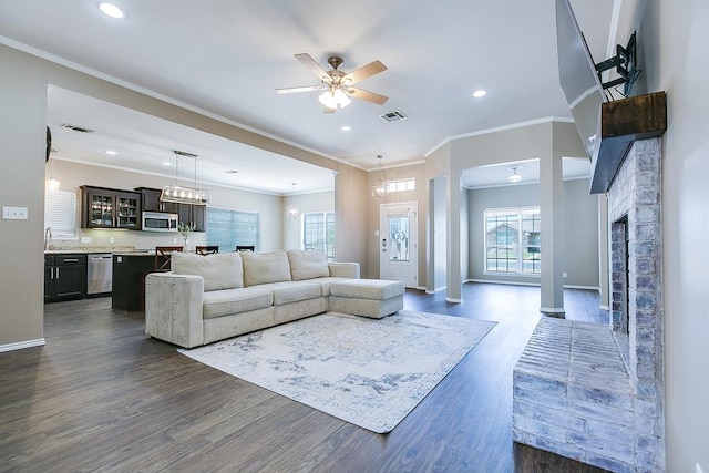 living room with dark wood-type flooring, ceiling fan, and crown molding