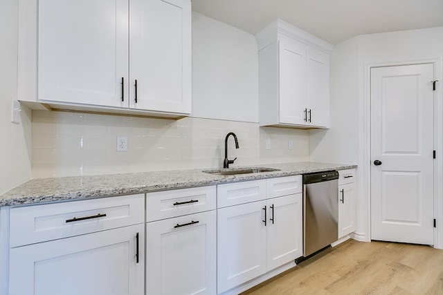 kitchen featuring a sink, stainless steel dishwasher, light wood-style floors, white cabinets, and light stone countertops