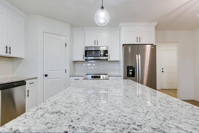 kitchen with stainless steel appliances, light stone countertops, tasteful backsplash, and white cabinetry