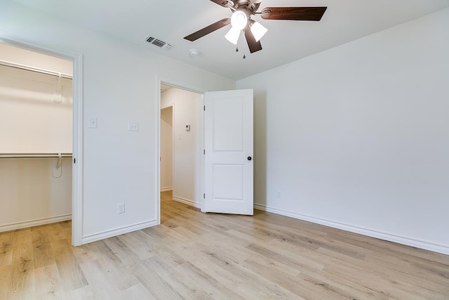 unfurnished bedroom with wood finished floors, visible vents, baseboards, a spacious closet, and a closet