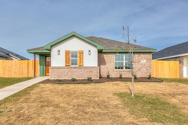 view of front of home with brick siding, a front yard, and fence