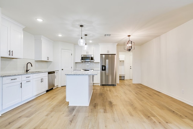 kitchen featuring stainless steel appliances, white cabinets, and decorative light fixtures