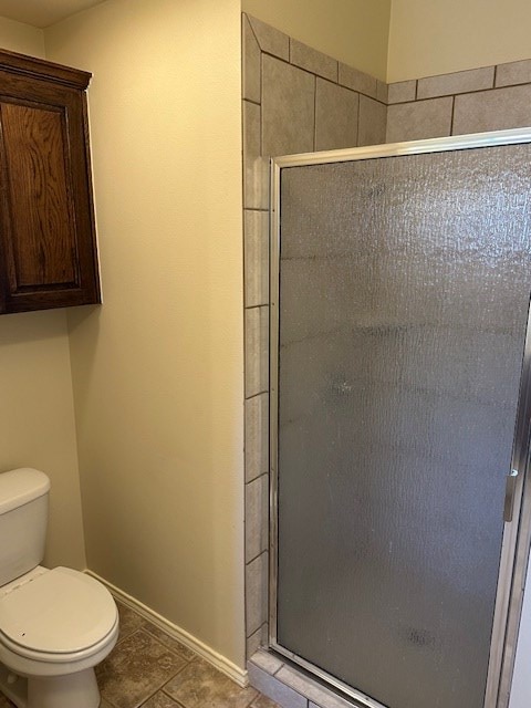 bathroom with tile patterned flooring, walk in shower, and toilet