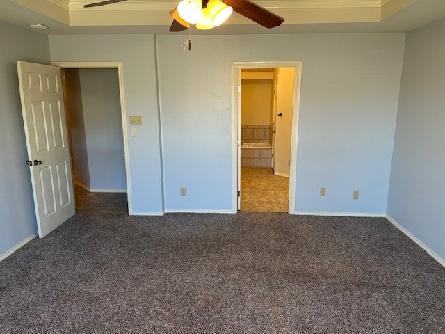 unfurnished bedroom with dark carpet and ceiling fan