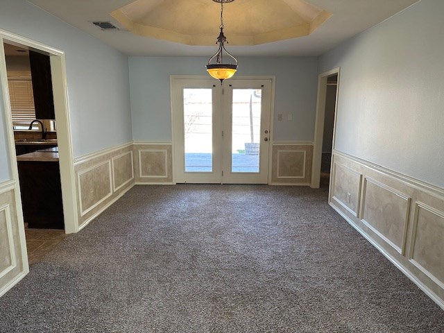 spare room with sink, a raised ceiling, and carpet