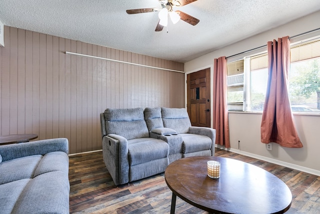 living room featuring dark wood-type flooring, wooden walls, and a textured ceiling