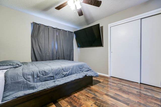 bedroom with dark wood-type flooring, ceiling fan, a closet, and a textured ceiling