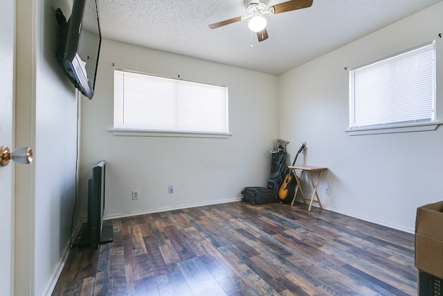 unfurnished room with dark wood-type flooring, ceiling fan, a textured ceiling, and a wealth of natural light