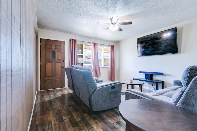 living room with a textured ceiling, dark wood-type flooring, and ceiling fan