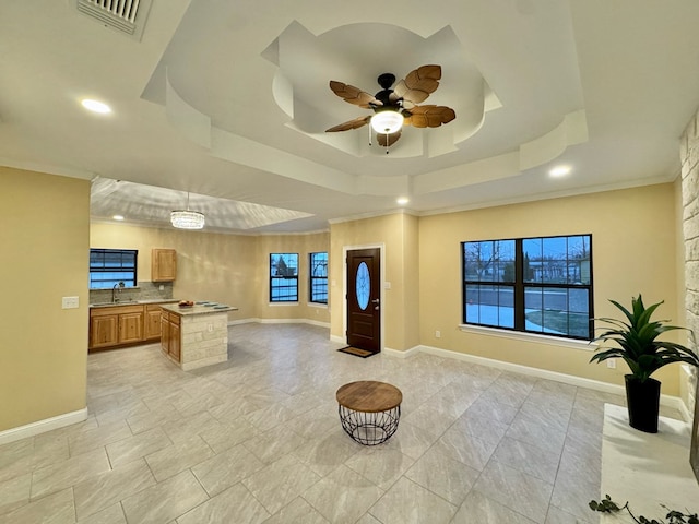 kitchen featuring sink, ceiling fan, a raised ceiling, crown molding, and plenty of natural light