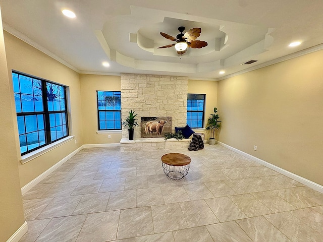 living area featuring a fireplace, ornamental molding, a raised ceiling, and ceiling fan