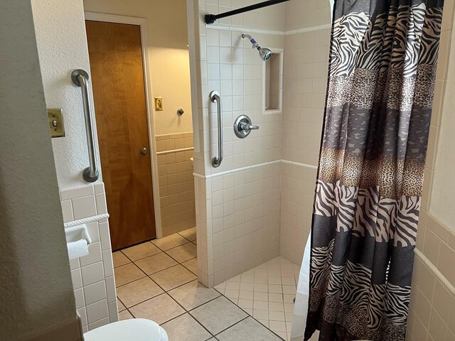 3826 Hillcrest Dr, San Angelo, TX 76904 - bathroom featuring tile patterned floors, a wainscoted wall, tiled shower, and tile walls