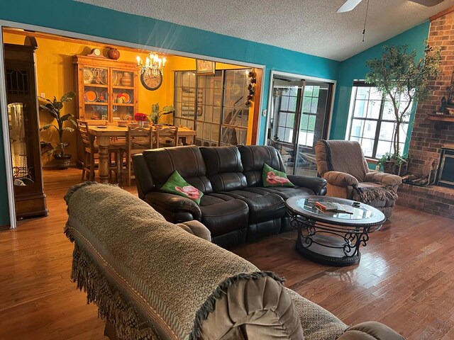 3826 Hillcrest Dr, San Angelo, TX 76904 - living area featuring wood finished floors, ceiling fan with notable chandelier, a fireplace, a textured ceiling, and lofted ceiling