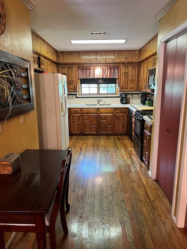 3826 Hillcrest Dr, San Angelo, TX 76904 - kitchen with dark wood-style floors, a sink, brown cabinetry, black appliances, and light countertops