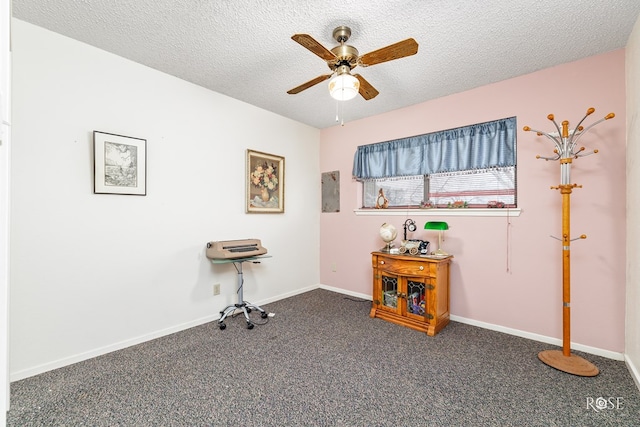 misc room featuring ceiling fan, a textured ceiling, and dark colored carpet