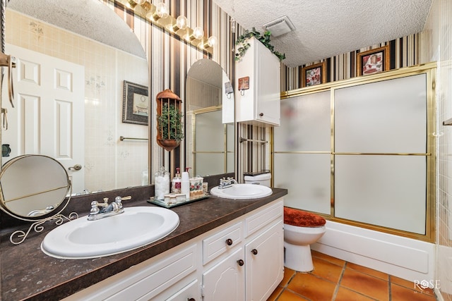 full bathroom featuring enclosed tub / shower combo, vanity, toilet, tile patterned floors, and a textured ceiling