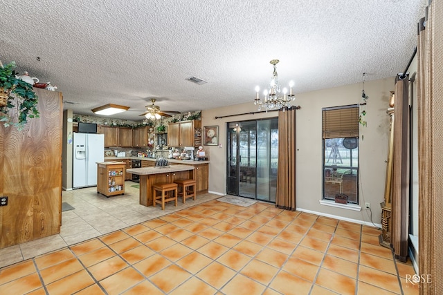 kitchen featuring light tile patterned flooring, decorative light fixtures, a breakfast bar area, white refrigerator with ice dispenser, and kitchen peninsula