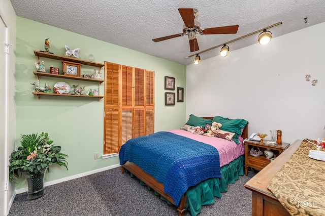 carpeted bedroom with ceiling fan, track lighting, and a textured ceiling