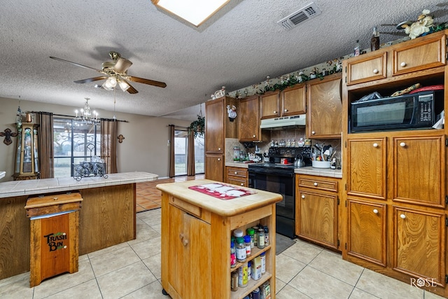 kitchen with light tile patterned floors, tile countertops, black appliances, and a center island