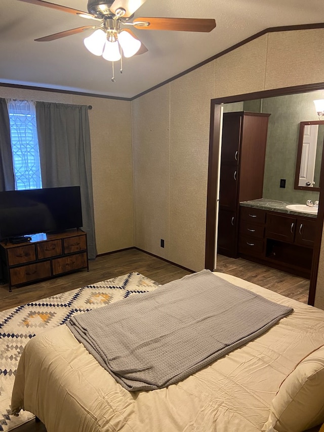 bedroom with sink, crown molding, light hardwood / wood-style flooring, ceiling fan, and vaulted ceiling