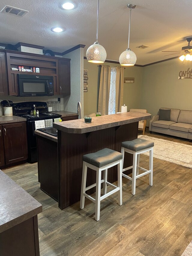 kitchen featuring dark hardwood / wood-style floors, an island with sink, and black appliances