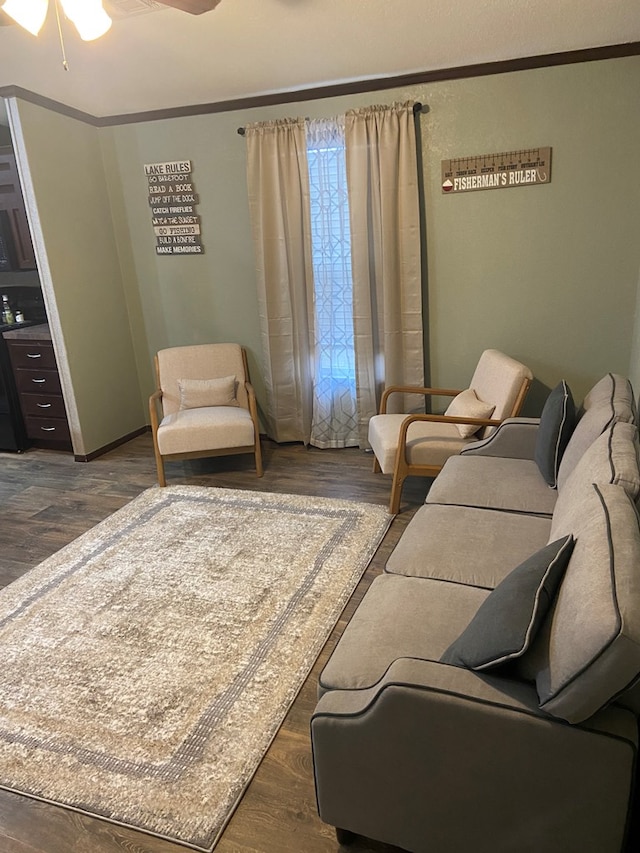 living room with ornamental molding, dark wood-type flooring, and ceiling fan