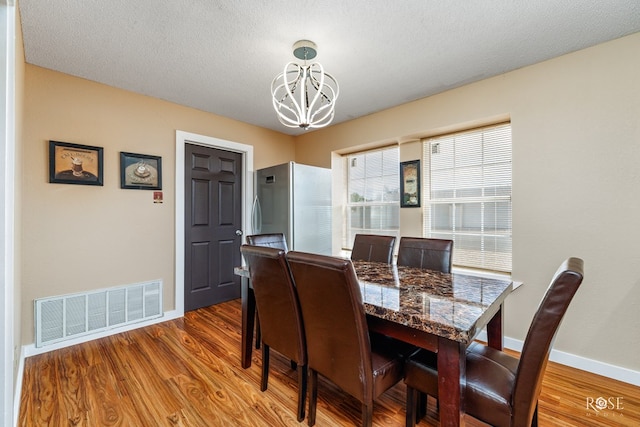 307 E 12th St, Big Lake, TX 76932 - dining area with wood finished floors, a textured ceiling, baseboards, visible vents, and an inviting chandelier
