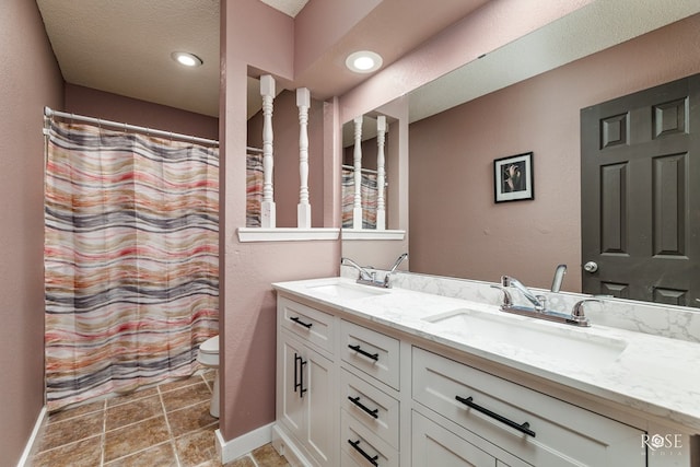 307 E 12th St, Big Lake, TX 76932 - bathroom featuring double vanity, toilet, baseboards, and a sink
