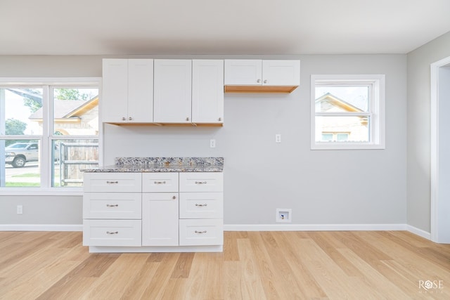 kitchen featuring white cabinetry, light stone counters, and plenty of natural light