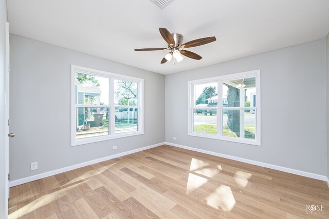 spare room with ceiling fan, a wealth of natural light, and light wood-type flooring