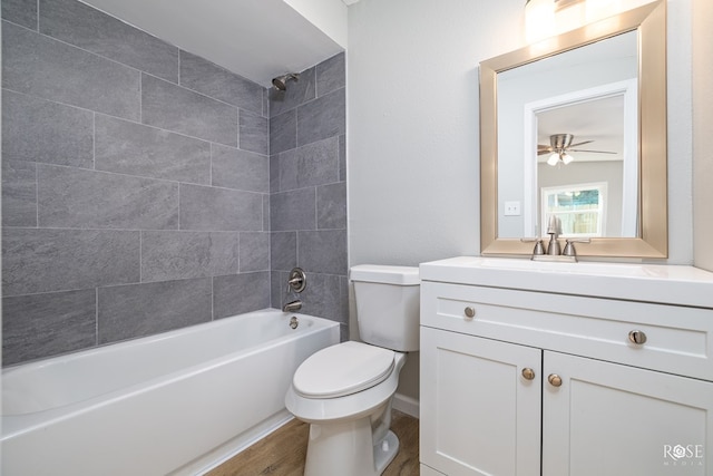 full bathroom featuring vanity, hardwood / wood-style floors, tiled shower / bath combo, and toilet