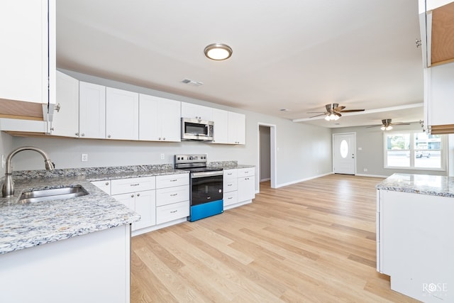 kitchen featuring sink, light stone counters, light hardwood / wood-style flooring, appliances with stainless steel finishes, and white cabinets