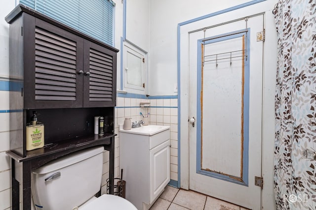 2318 Dallas St, San Angelo, TX 76901 - bathroom featuring tile patterned flooring, vanity, toilet, tile walls, and a wainscoted wall
