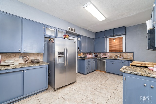 2318 Dallas St, San Angelo, TX 76901 - kitchen with visible vents, blue cabinets, a sink, backsplash, and stainless steel appliances