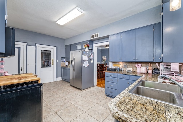2318 Dallas St, San Angelo, TX 76901 - kitchen featuring visible vents, blue cabinets, stainless steel fridge with ice dispenser, a sink, and gas stove