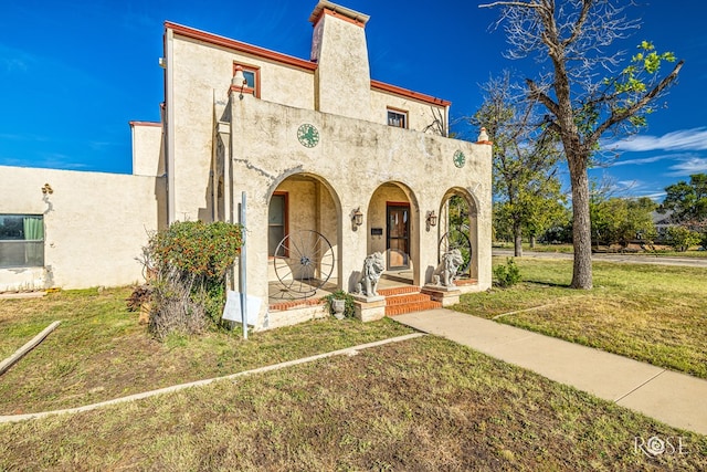 2318 Dallas St, San Angelo, TX 76901 - mediterranean / spanish-style house featuring covered porch, stucco siding, a chimney, and a front lawn
