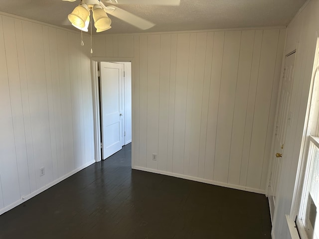 unfurnished room with dark hardwood / wood-style flooring, ceiling fan, a textured ceiling, and wood walls