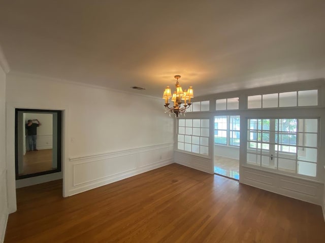 1001 S David St, San Angelo, TX 76903 - unfurnished dining area featuring a chandelier, dark wood finished floors, crown molding, a decorative wall, and wainscoting