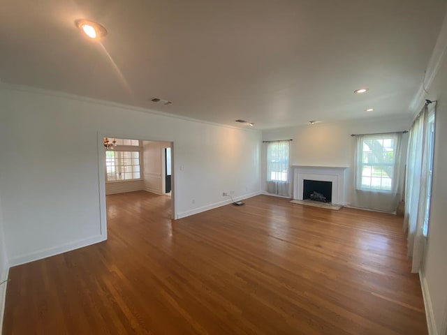 1001 S David St, San Angelo, TX 76903 - unfurnished living room with ornamental molding, a fireplace with flush hearth, healthy amount of natural light, wood finished floors, and baseboards
