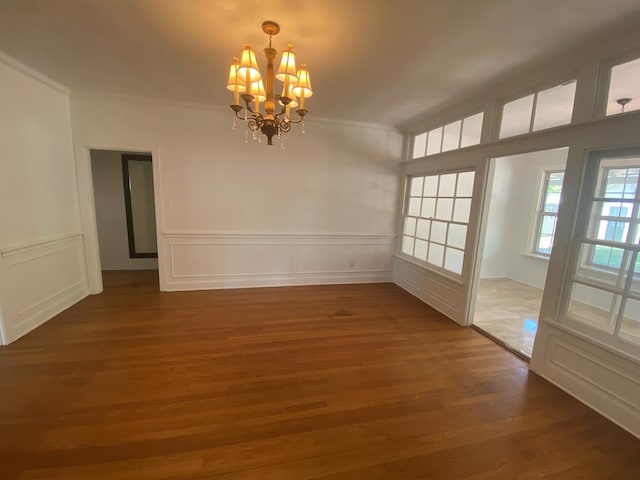 1001 S David St, San Angelo, TX 76903 - unfurnished dining area featuring a chandelier, wood finished floors, crown molding, a decorative wall, and a wainscoted wall
