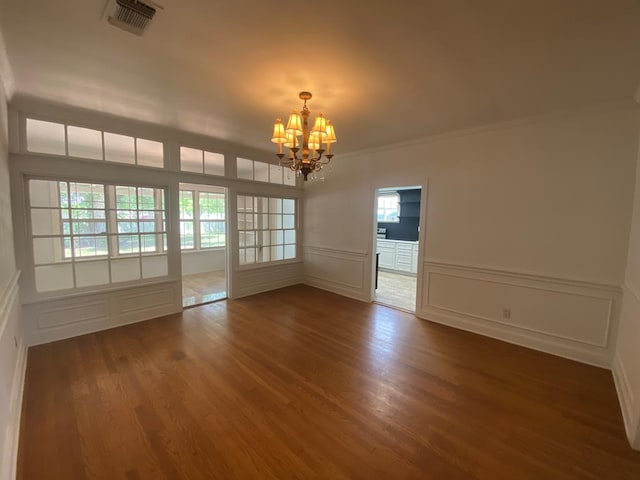 1001 S David St, San Angelo, TX 76903 - unfurnished room featuring a chandelier, a decorative wall, wood finished floors, plenty of natural light, and ornamental molding