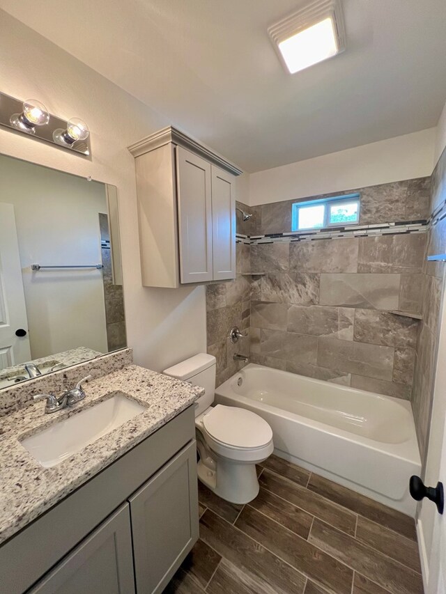 full bathroom featuring tiled shower / bath, vanity, and toilet