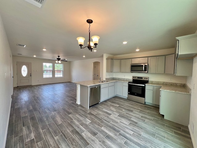 kitchen featuring decorative light fixtures, appliances with stainless steel finishes, gray cabinets, kitchen peninsula, and light stone countertops