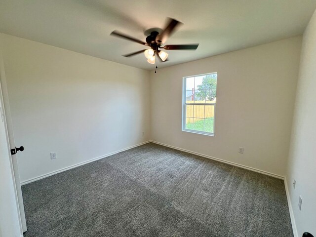 spare room featuring dark carpet and ceiling fan