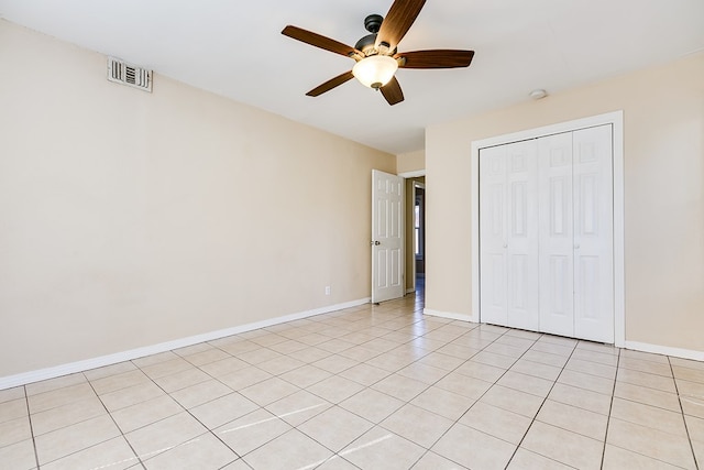 unfurnished bedroom with light tile patterned flooring, ceiling fan, and a closet