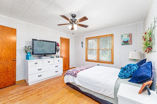 bedroom featuring ceiling fan, ornamental molding, and light hardwood / wood-style flooring