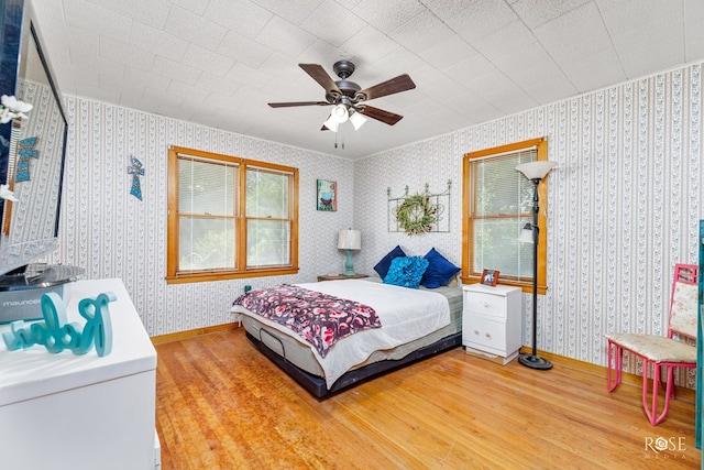 bedroom featuring hardwood / wood-style floors, ornamental molding, and ceiling fan