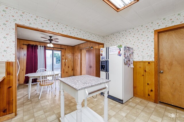 kitchen with ceiling fan, wooden walls, and white fridge with ice dispenser